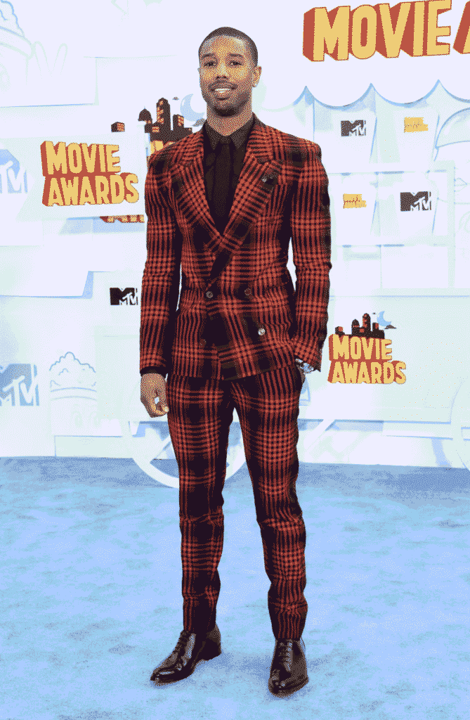Michael B. Jordan red plaid suit at MTV Michael B. Jordan posing in a bold red plaid double-breasted suit with a black shirt at the MTV Movie Awards — playful, sharp, and attention-grabbing