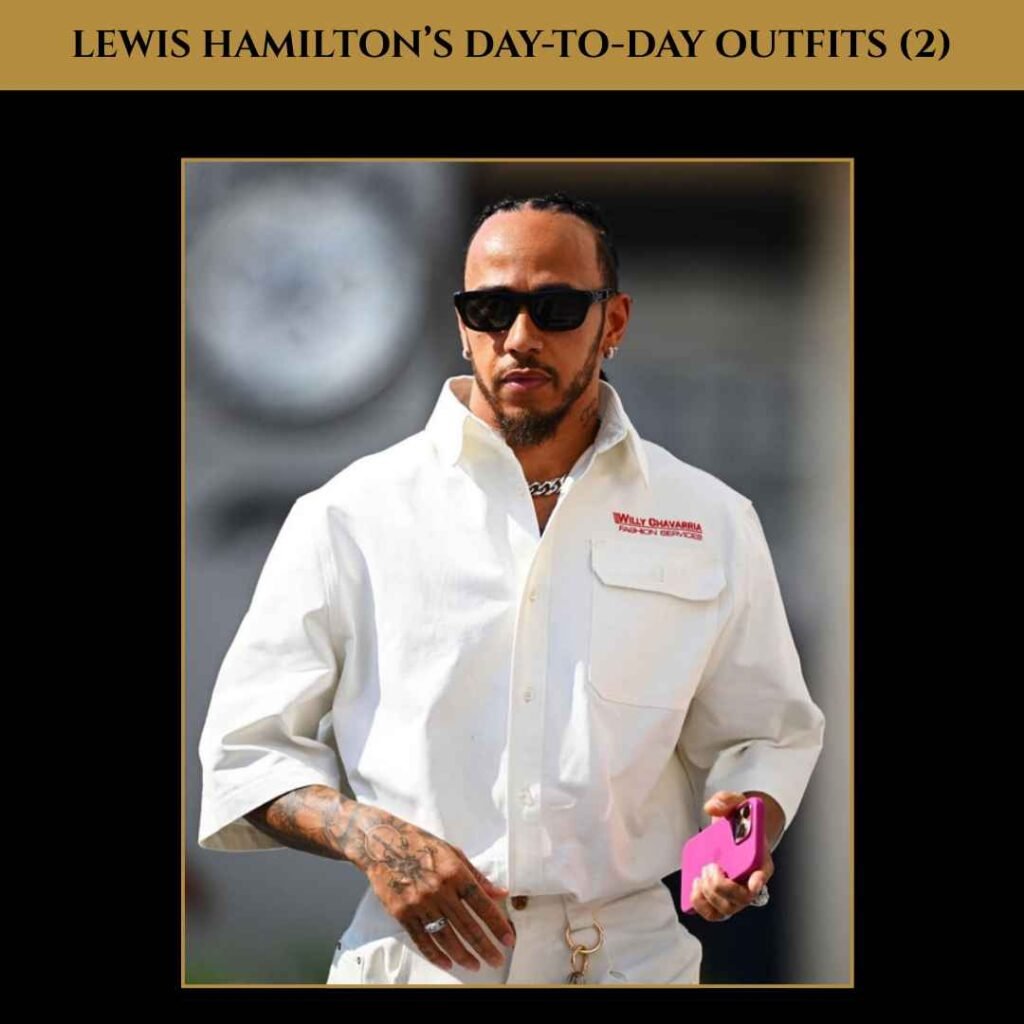 Lewis Hamilton Day-to-Day Outfit (2) Lewis Hamilton wearing a white jumpsuit with rolled sleeves, holding a pink phone and sunglasses, showcasing his casual day-to-day outfit.