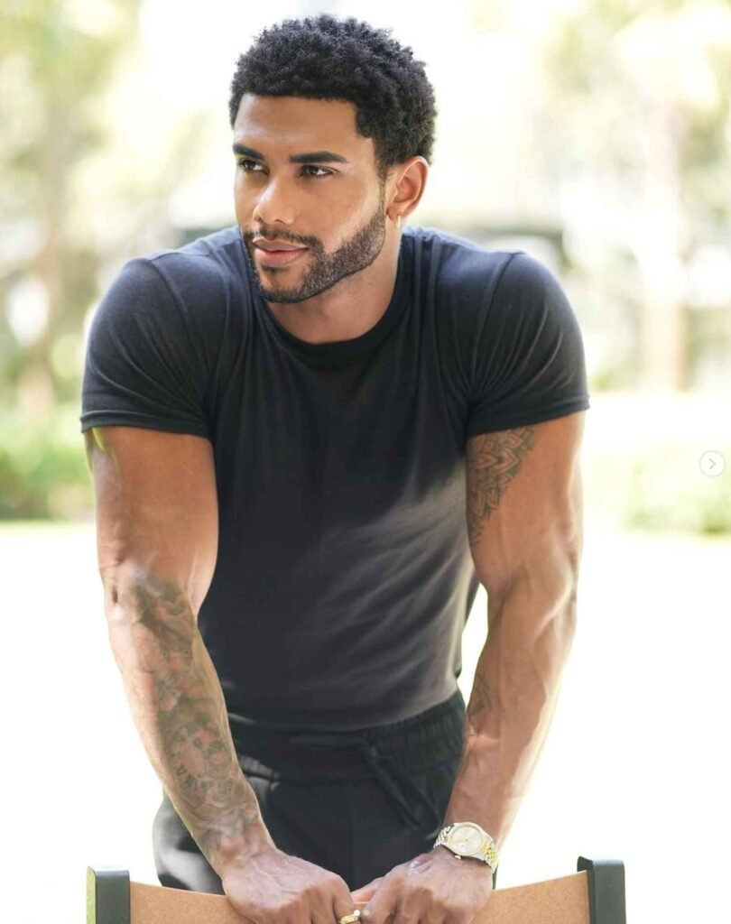 Austin Dunham with short curly hair, beard, and tattoos, showcasing a clean men’s curly hairstyle.